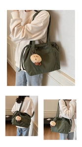 Detail of dark green corduroy tote bag with drawstring closure and cute plush charm