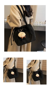 Detail of black corduroy tote bag with drawstring closure and cute chick plush charm