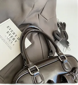Detailed view of dark brown patent leather handbag with contrasting white stitching accents