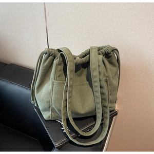 Detailed view of green corduroy tote bag featuring drawstring closure and front pocket