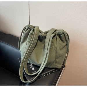 Detailed view of green corduroy tote bag with drawstring closure and outer pocket texture