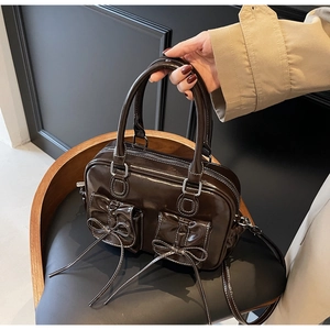 Detail of dark brown retro handbag with contrast stitching and bow flap pockets