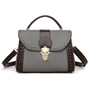Minimalist grey twill and brown leather crossbody handbag with gold clasp on white background