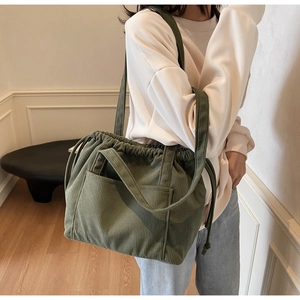 Detail of dark green corduroy tote bag showing the drawstring closure and ribbed texture