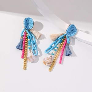 Boucles d'oreilles bohèmes à pompons avec chaînes bleues et coquillages sur fond blanc