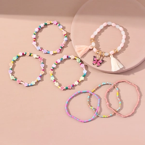 Dettaglio del ciondolo a farfalla rosa e nappa sul set di bracciali boho