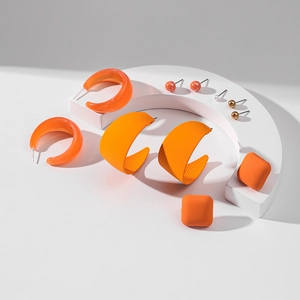 Ensemble chic de boucles d'oreilles en acrylique orange avec créoles et perles sur blanc