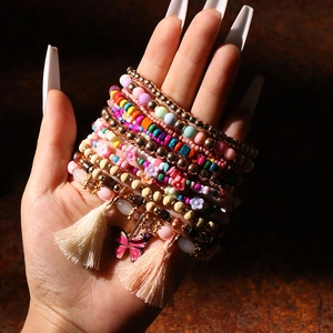 Dettaglio del set di braccialetti bohémien colorati con nappe e ciondolo farfalla
