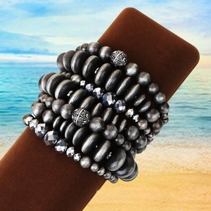Dettaglio del set di braccialetti multistrato con perle metalliche grigie e ciondoli intagliati