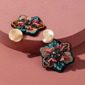 Vue détaillée de boucles d'oreilles brodées de fleurs bohèmes avec perles et clou doré