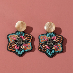 Détails de boucles d'oreilles brodées avec pierre grise centrale et perles fines