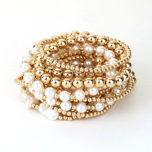 Detail of 13-piece beaded bracelet set featuring gold metal beads and white faux pearls