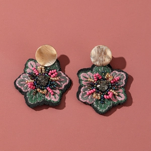 Détails de boucles d'oreilles fleuries faites main avec broderie et cristal central poli