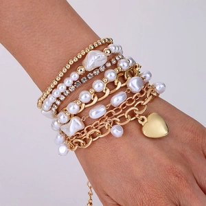 Gros plan d'un bracelet multi-rangs en perles avec pendentif cœur doré et strass brillants