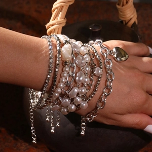 Détail d'un ensemble de bracelets en perles avec pendentif cœur et chaînes strass au poignet