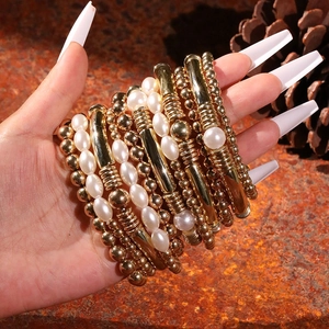 Détail d'un ensemble de bracelets dorés à plusieurs rangs avec perles sur le poignet
