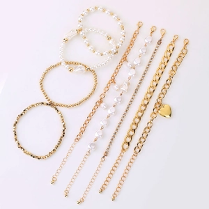 Vue détaillée d'un ensemble de 9 bracelets dorés avec perles, strass et pendentif en cœur
