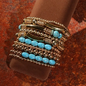 Détail de bracelets bohèmes avec perles turquoise et dorées sur support rustique