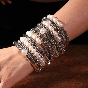 Détail d'un ensemble de bracelets multicouches avec perles et perles argentées au poignet