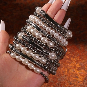 Détail de bracelets superposés bohèmes avec perles blanches et perles en métal argenté