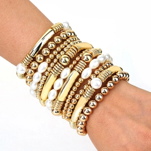 Détail d'un bracelet multicouche avec perles en métal doré et perles nacrées blanches