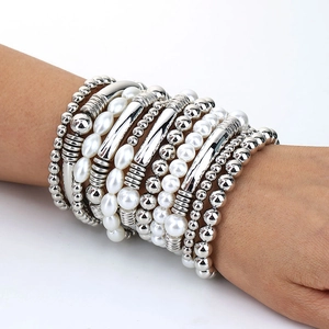 Détail de bracelets perlés multicouches avec tubes métalliques argentés et perles nacrées