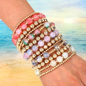 Handmade multilayer crystal bead bracelet set with gold beads on a sunny beach background