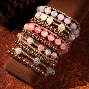 Close-up of bohemian multilayer beaded bracelets with rose gold beads and floral stones