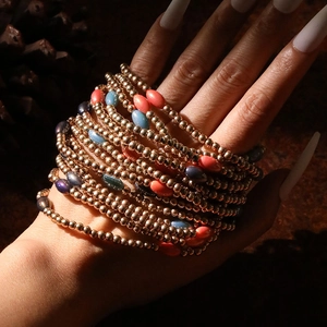 Detail of layered gold and colorful beaded stretch bracelets on a model wrist