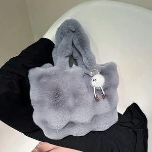 Plush grey faux fur bucket bag with a cute monster charm for winter fashion styles