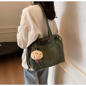 Detail of dark green corduroy tote bag with drawstring closure and cute potato charm