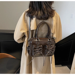 Model wearing a vintage dark brown glossy handbag with bows and beige trench coat