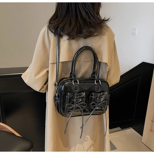 Detail of vintage black patent leather bag with bow pockets and white contrast stitching