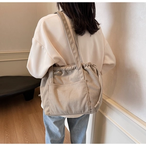 Detail of beige corduroy tote bag showing soft ribbed texture and drawstring closure