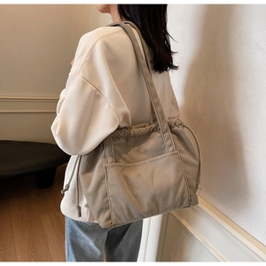 Detail of khaki corduroy tote bag showing drawstring closure and front pocket