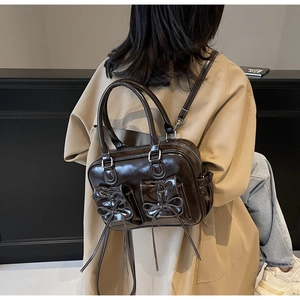 Detail of vintage dark brown tote with bow pockets shown on trench coat shoulder