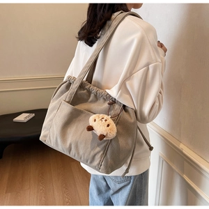 Detail of khaki corduroy tote bag showing ribbed texture and plush bear charm