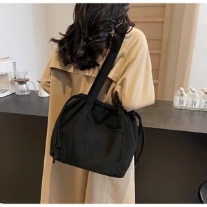 Detail of black corduroy tote bag with drawstring closure and large front pocket