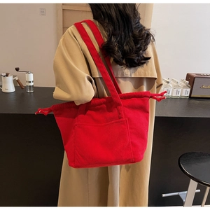 Detail of red corduroy tote bag featuring drawstring closure and soft texture fabric