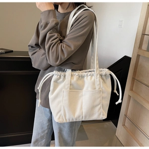 Detail of white corduroy tote bag with drawstring closure and two front pockets