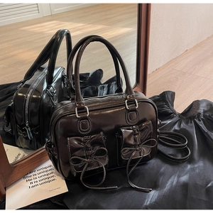 Detailed close-up of a vintage leather handbag with bow pockets and white stitching