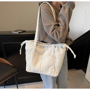 Detail of white corduroy tote bag showing drawstring closure and front pockets