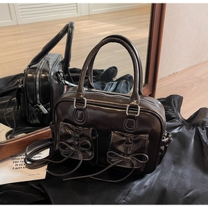 Detail of glossy patent leather mini bag with decorative bow and silver hardware