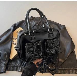 Detail of black patent leather bag with white contrast stitching and bow accents