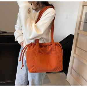 Detail of orange corduroy tote bag with drawstring closure and large front pocket