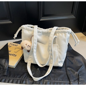Detailed texture of off-white corduroy tote bag with drawstring closure and bear charm