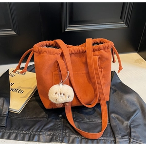 Detail of orange corduroy tote bag with drawstring, pocket and plush animal charm