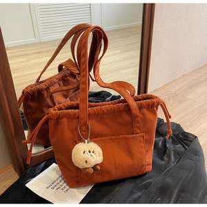 Detail of caramel corduroy tote bag with drawstring closure and cute plush charm