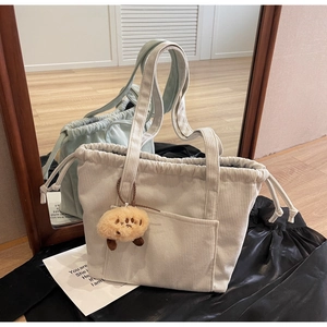 Detail view of corduroy tote bags with drawstring closure and cute dog plush pendant