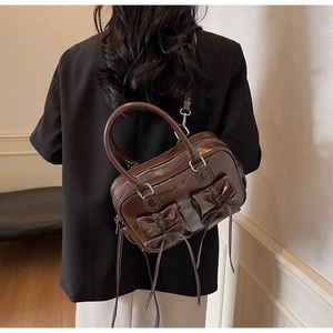 Detailed view of vintage brown crossbody bag featuring elegant bow and long tassel accents